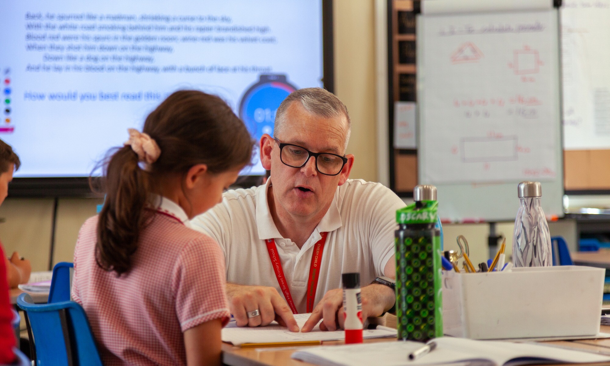 Exchange Teacher Training Image of trainee teacher explaining to a young pupil